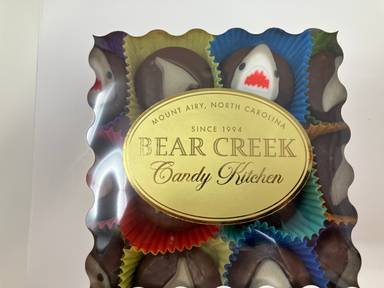 Box of Bear Creek Candy Kitchen chocolates with colorful wrappers on a white background